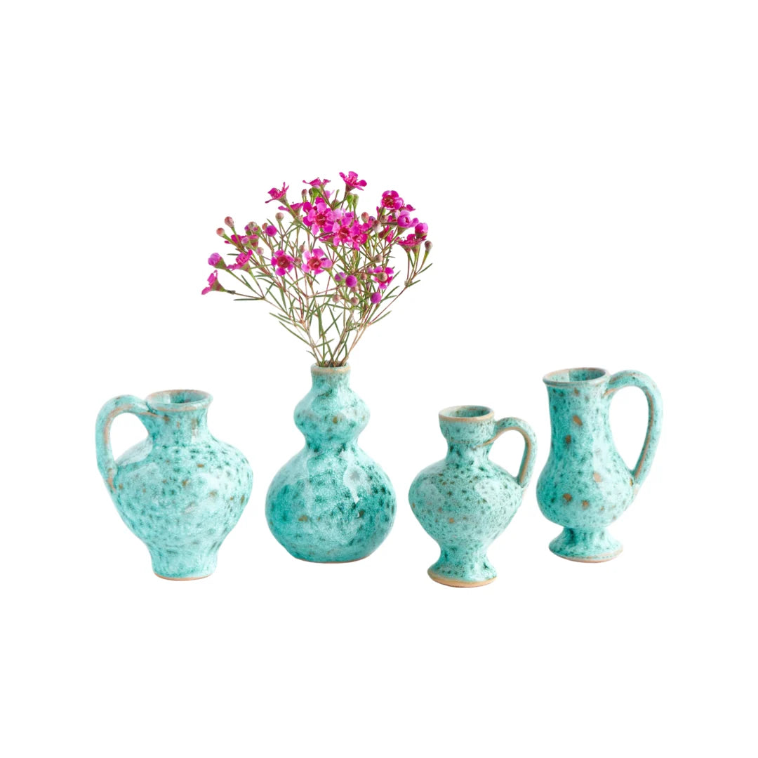 Carolina Irving & Daughters Mini Seafoam Bud Vases, set of four mottled green shapes, one holding pink flowers.